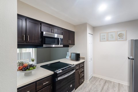 A kitchen with dark brown cabinets and a black stove top.