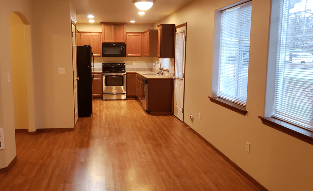 an empty kitchen with wood flooring and
