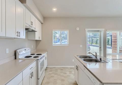 A kitchen with white cabinets and a tiled floor.