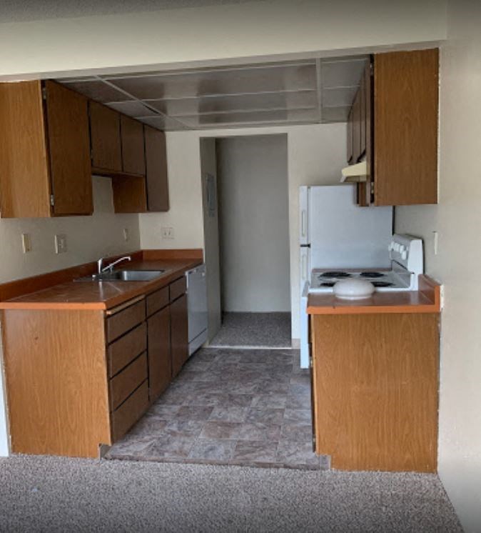 an empty kitchen with wooden cabinets and a white refrigerator