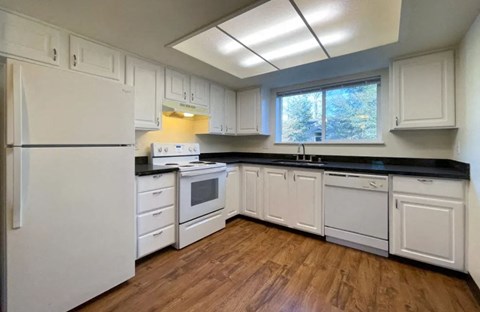 a kitchen with white cabinets and appliances and a window