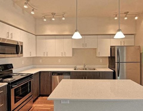 A kitchen with a white counter top and stainless steel appliances.