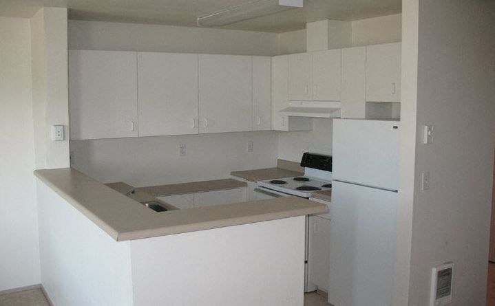 an empty kitchen with a stove and a refrigerator