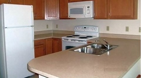 A kitchen with a white fridge, microwave, and stove.