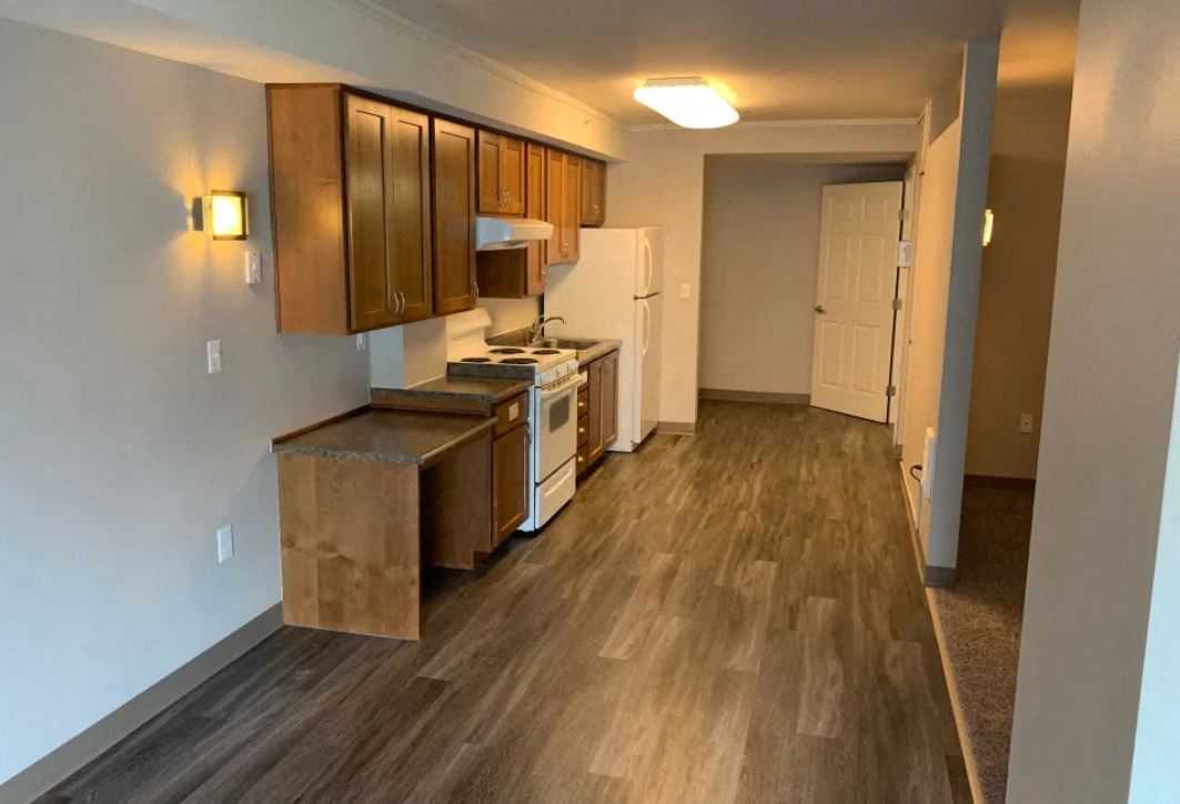 a kitchen with wood floors and cabinets and a white refrigerator