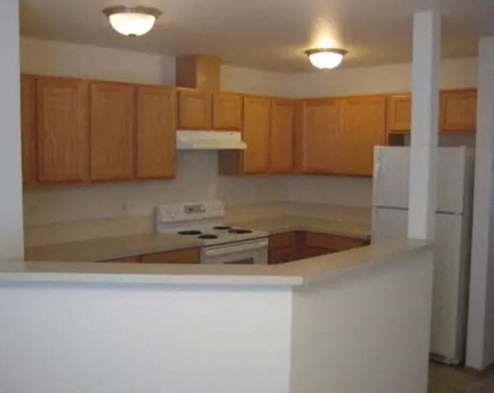 an empty kitchen with a stove and a refrigerator