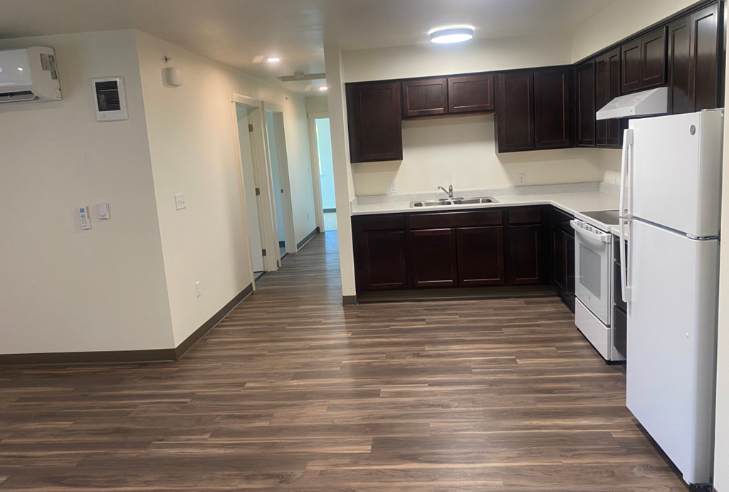 an empty kitchen with white appliances and dark wood cabinets