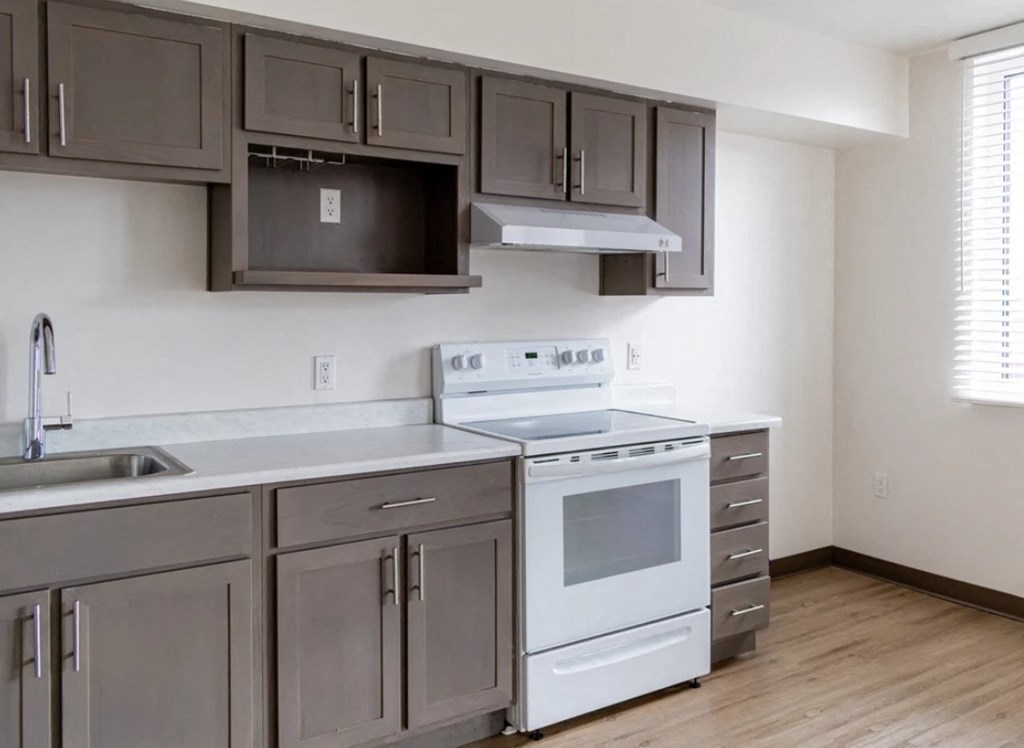 A kitchen with a white stove top oven and white cabinets.