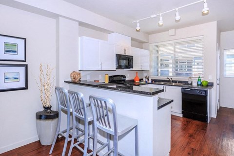 A kitchen with white cabinets and a black countertop.