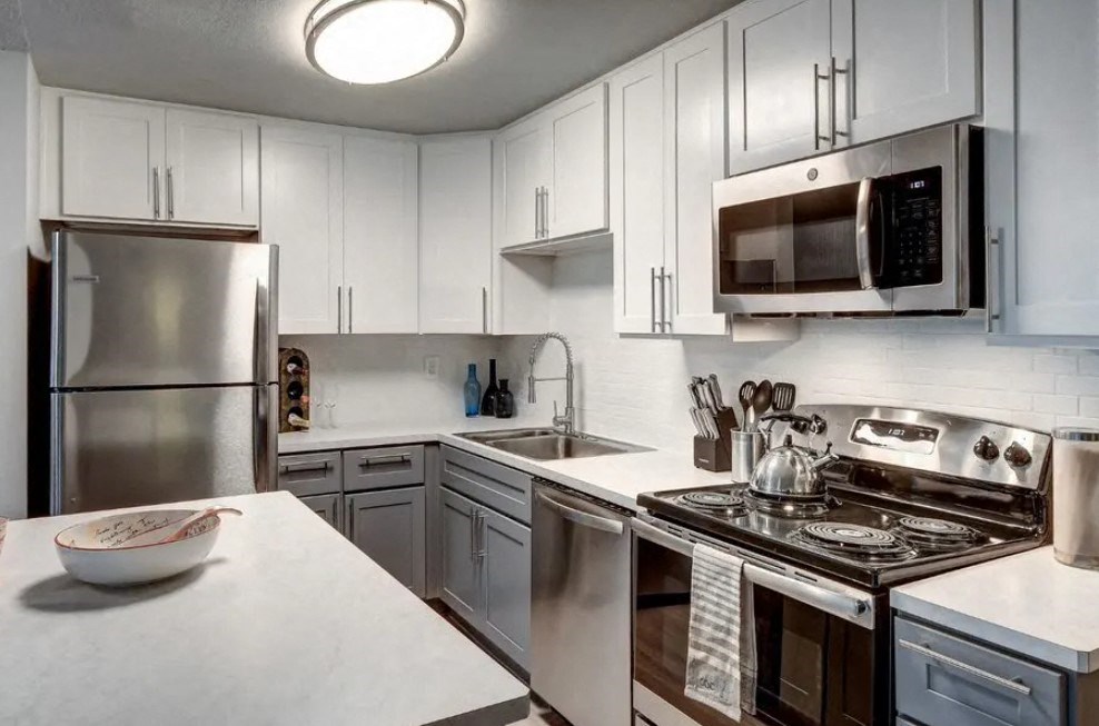 A modern kitchen with a stainless steel refrigerator, microwave, and oven.