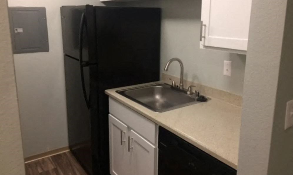 a kitchen with a sink and a black refrigerator