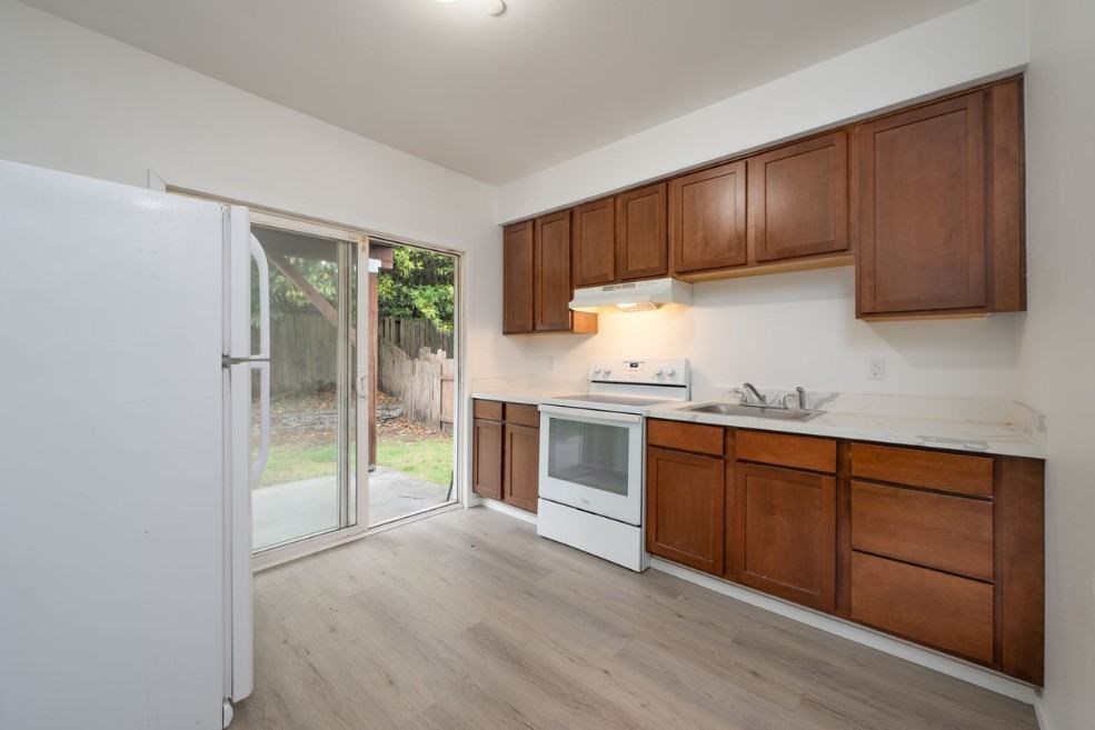 A kitchen with white appliances and wooden cabinets.