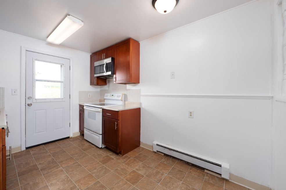 A kitchen with white walls and brown cabinets.