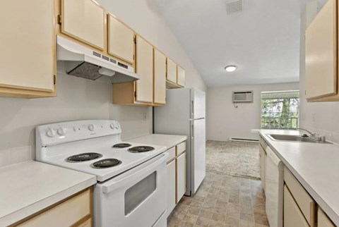 A kitchen with a white stove top oven and white cabinets.