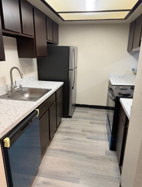 A kitchen with a black fridge and a black dishwasher.