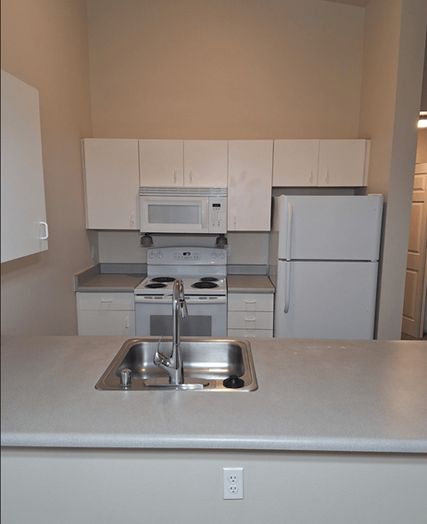 a kitchen with white cabinets and appliances and a sink