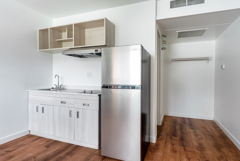 A kitchen with a refrigerator, sink, and wooden cabinets.