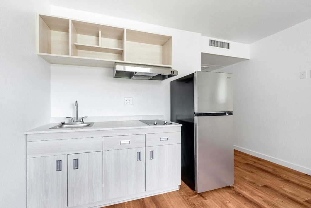 A kitchen with a sink, a refrigerator, and cabinets.