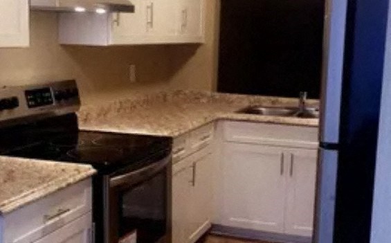 a kitchen with white cabinets and a black stove