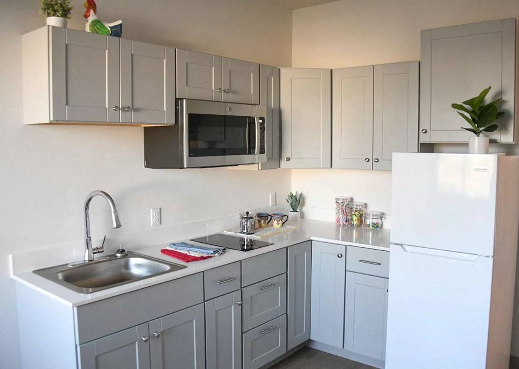 a kitchen with gray cabinets and a sink and a refrigerator
