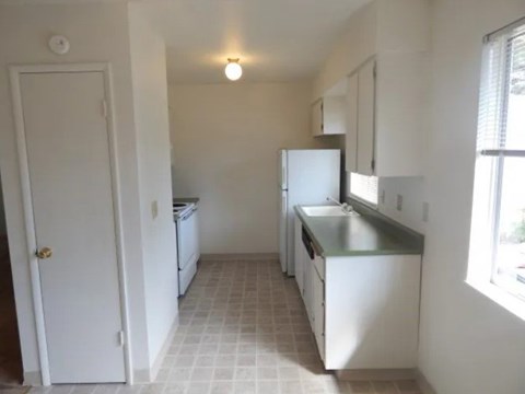 A kitchen with white appliances and a white door.