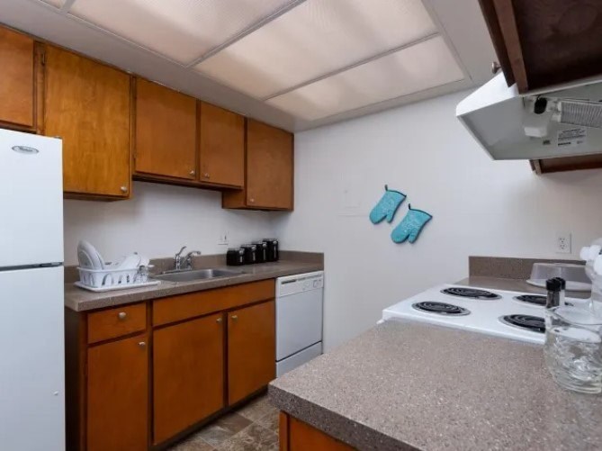 A kitchen with brown cabinets and a white fridge.