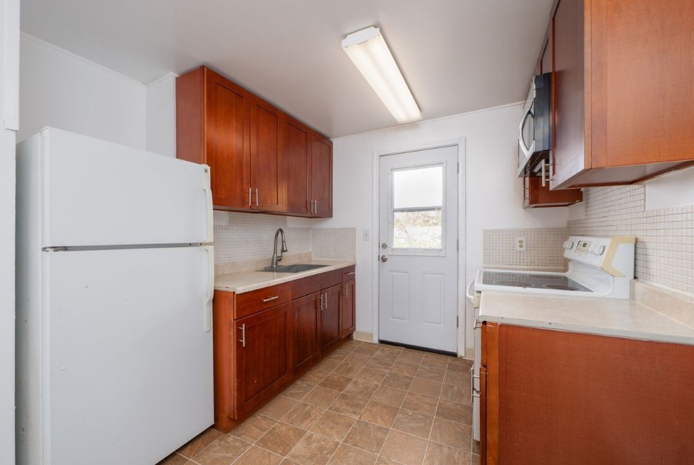 A kitchen with brown cabinets and a white refrigerator.