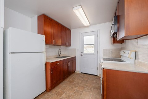 A kitchen with brown cabinets and a white refrigerator.