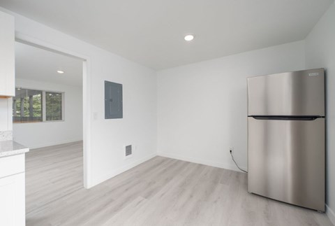 A modern kitchen with a stainless steel refrigerator and wooden flooring.