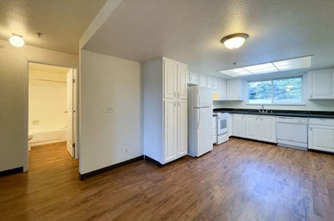 an empty kitchen with white cabinets and a wood floor