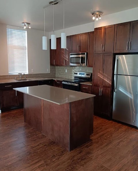 A kitchen with wooden cabinets and a stainless steel refrigerator.