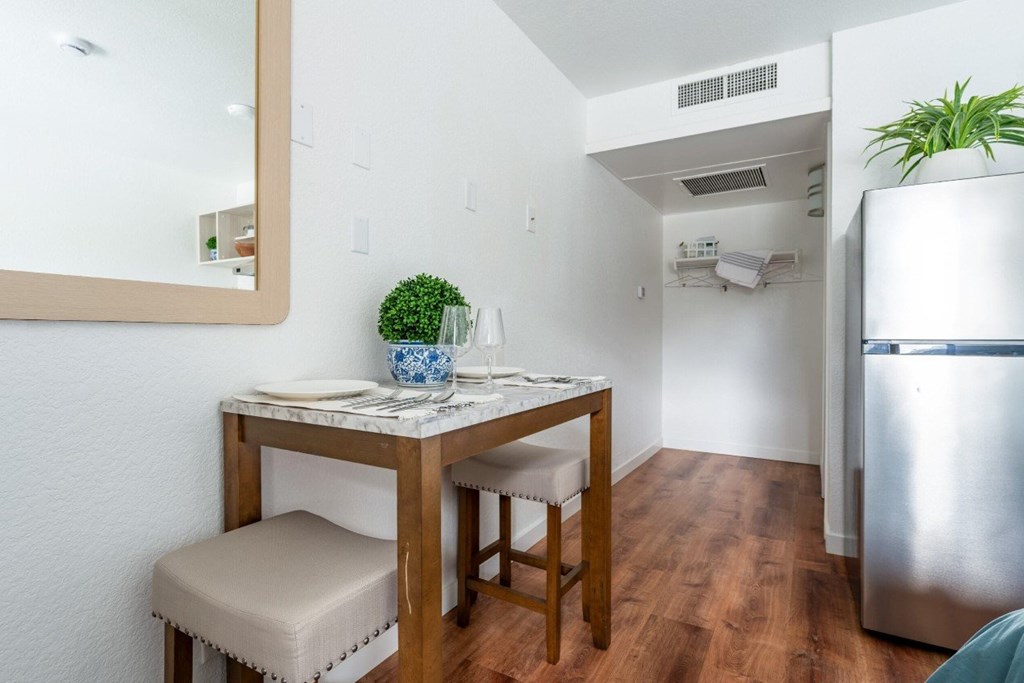 A small table with a plant on it and a chair with a white cushion.