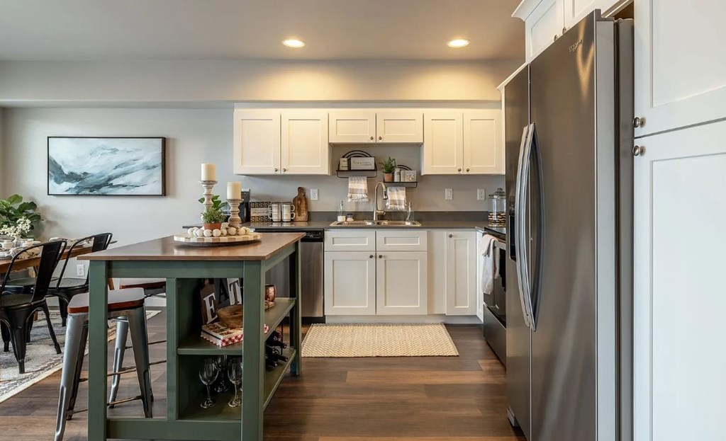 A kitchen with a refrigerator on the right and a table with chairs in the middle.