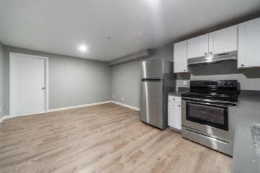 an empty kitchen with stainless steel appliances and a wooden floor