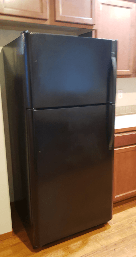 a black refrigerator in a kitchen with wood floors