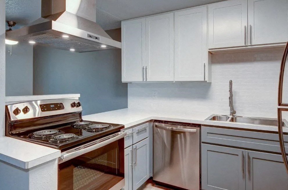 A modern kitchen with a stove, sink, and cabinets.