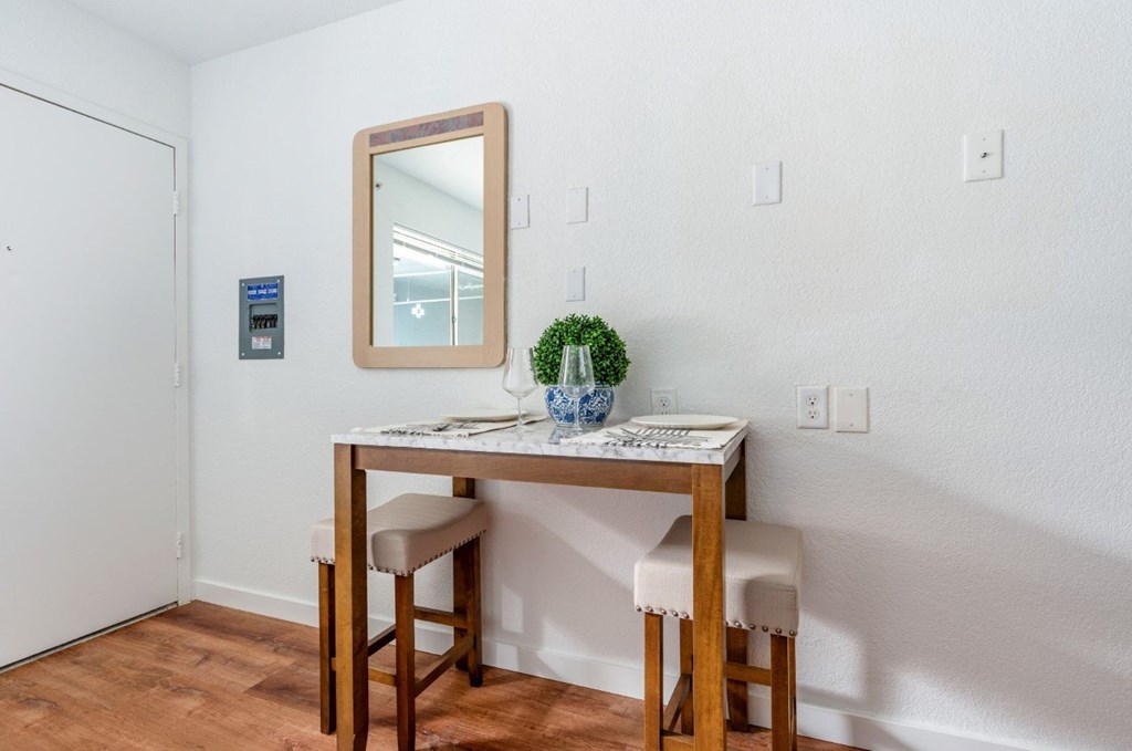 A small table with a mirror above it and two chairs.