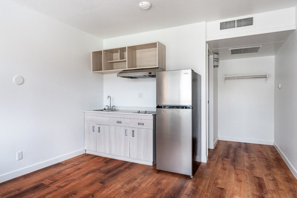 A kitchen with a stainless steel refrigerator and wooden floors.