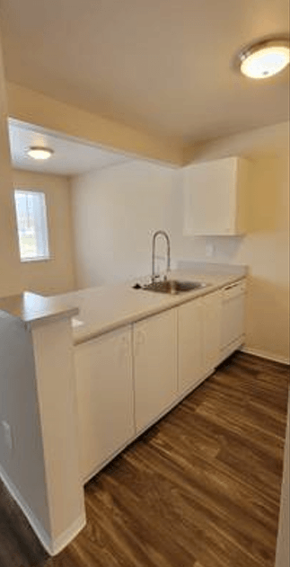 an empty kitchen with white cabinets and a sink