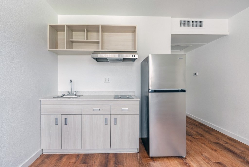 A modern kitchen with a stainless steel refrigerator and wooden floors.