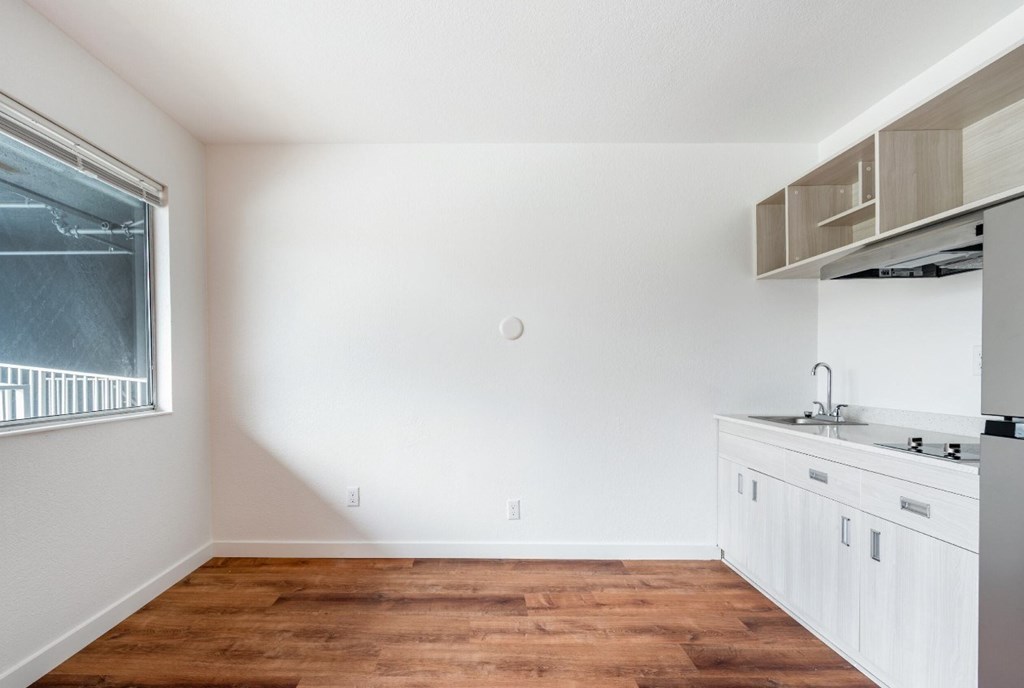 A kitchen with white cabinets and a wooden floor.