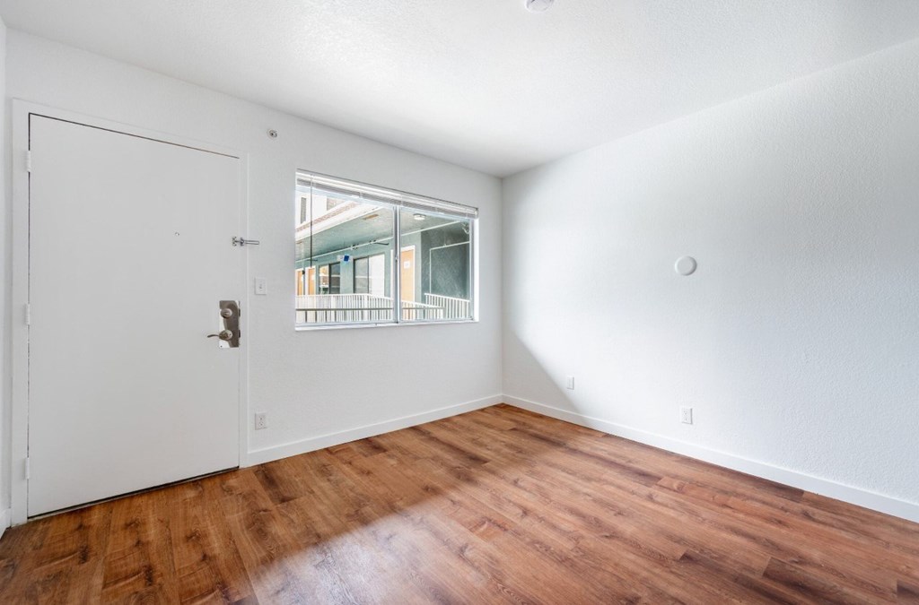 A room with a white door and wooden flooring.