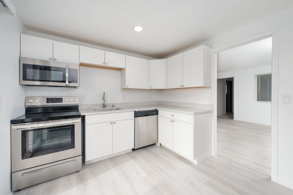 A modern kitchen with white cabinets and stainless steel appliances.