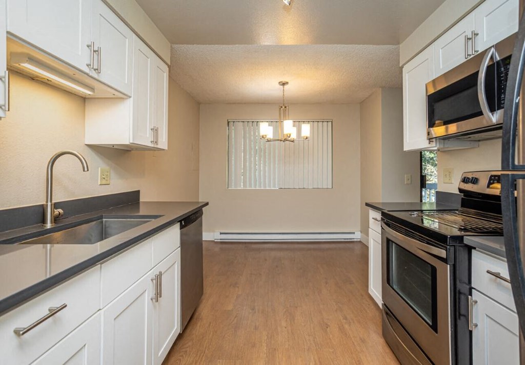a kitchen with white cabinets and black counter tops
