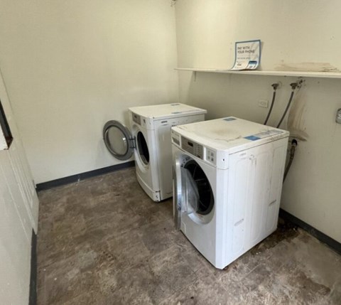 Two white front load washing machines in a laundry room.