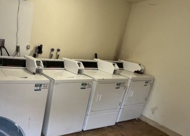 A row of washing machines are lined up in a laundry room.