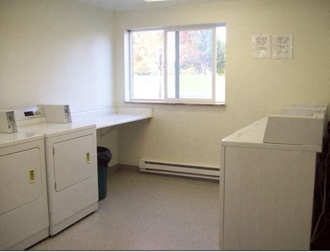 an empty laundry room with washing machines and a window