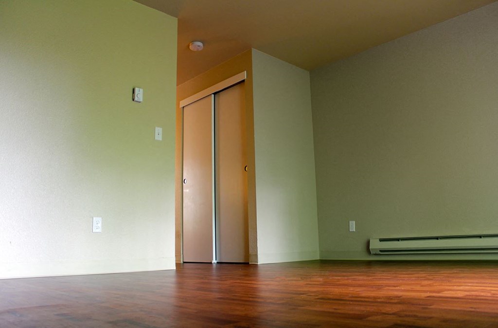 an empty living room with wood floors and a door