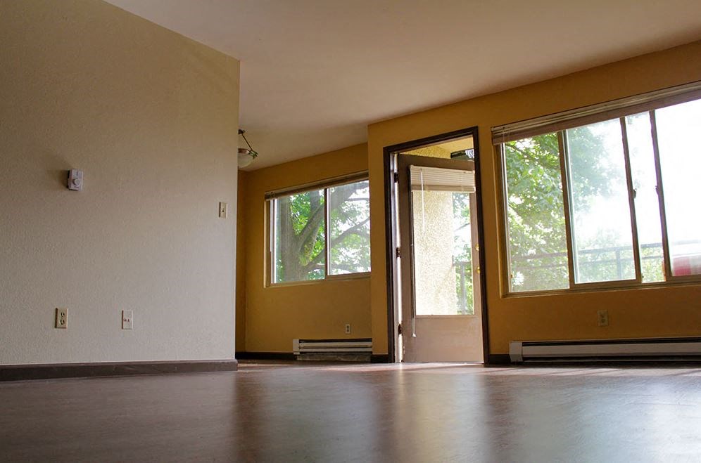 an empty living room with yellow walls and large windows