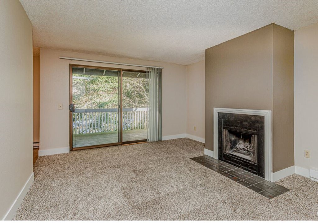 an empty living room with a fireplace and a sliding glass door